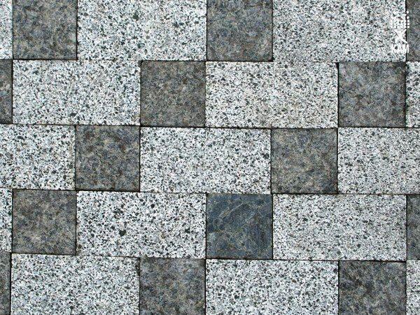 Ułożona szachownica z jasnoszarej i ciemnoszarej kostki o nieregularnej fakturze.