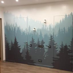 Like Denis Shapel - Wnętrze z pomalowaną ścianą i drzwiami w motyw lasu iglastego, z widocznymi włącznikami światła i lampkami ściennymi.
