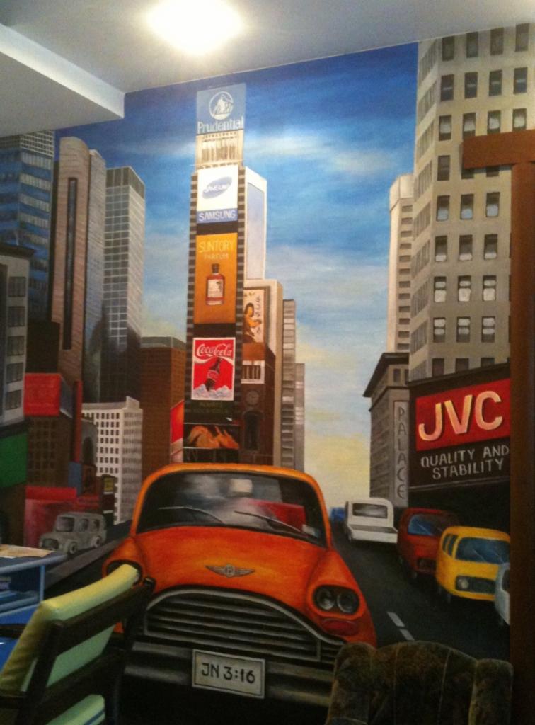 Malowidło ścienne przedstawiające Times Square z pomarańczową taksówką, widoczne fragmenty mebli w pomieszczeniu.