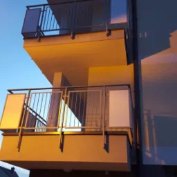 Nowoczesny budynek z balkonami z metalowymi balustradami, widok z dołu na elewację o zmierzchu.