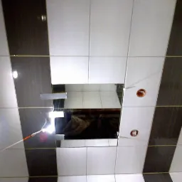 Układanie płytek w łazience: widok na sufit z biało-szarymi płytkami ułożonymi w pasy, otwory na oświetlenie i widoczne rury instalacyjne.