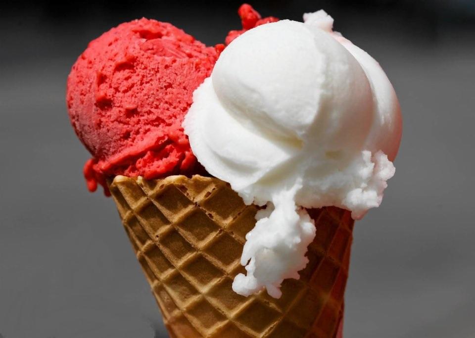 Wafel z dwiema gałkami lodów: intensywnie czerwonymi i śnieżnobiałymi, z delikatnie topiącymi się fragmentami.