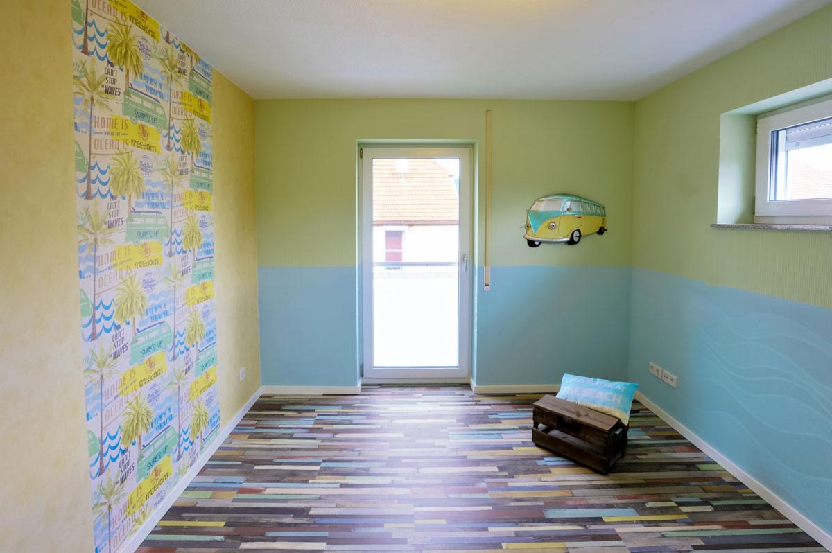 Pokój po remoncie w stylu plażowym: tapeta z palmami, ściany pomalowane na zielono i niebiesko, podłoga z paneli imitujących deski, dekoracja ścienna w kształcie Volkswagena Garbusa.