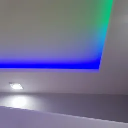 Podwieszany sufit z oświetleniem LED, barwa niebiesko-zielona, punktowe światło w rogu pomieszczenia, białe ściany.