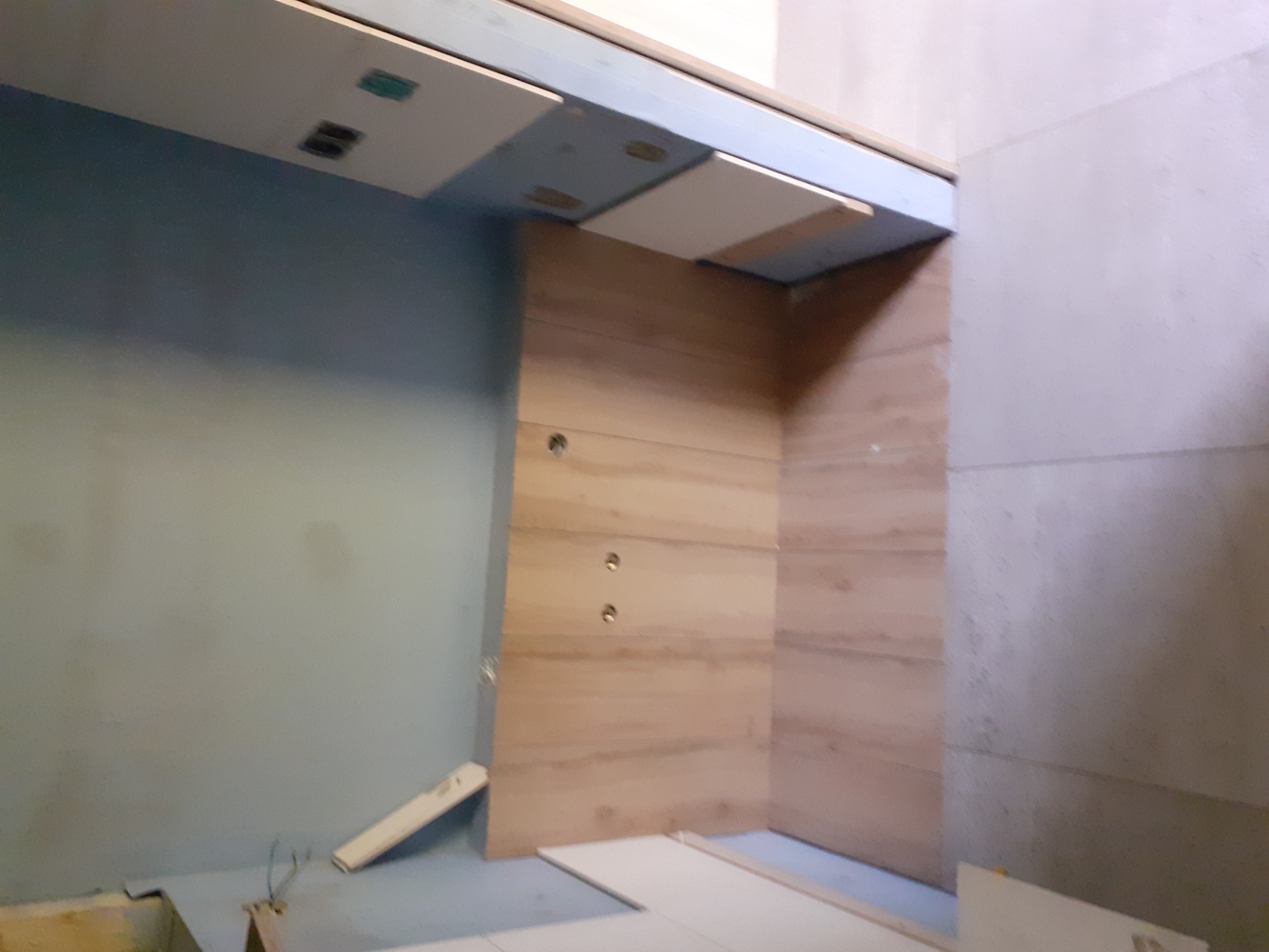 Wnętrze w trakcie prac wykończeniowych w Sosnowcu: drewniana boazeria na ścianie, częściowo zamontowane płyty sufitowe, surowa ściana obok.