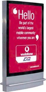 Podświetlany billboard reklamowy z logo Vodafone i hasłem 'Hello', umieszczony na metalowej konstrukcji z szarymi profilami.