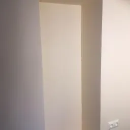 Wnęka w ścianie po wykonaniu prac wykończeniowych, pomalowana na biało, widoczny kontakt elektryczny.