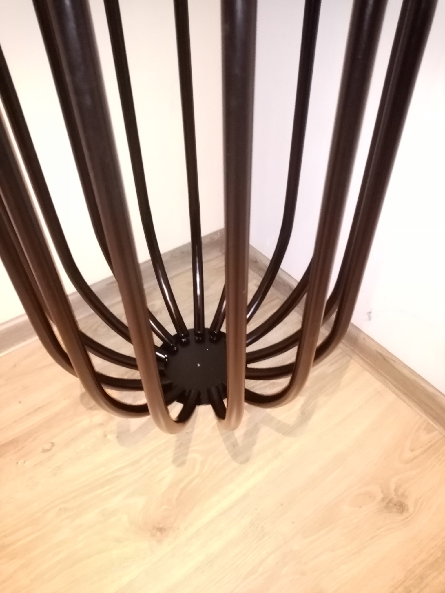 Metalowa podstawa stolika kawowego w stylu loft z giętych rurek, widok z góry na parkiet.