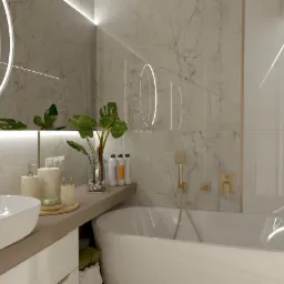 Elegancka łazienka z marmurowymi płytkami, okrągłym lustrem podświetlanym LED, białą umywalką nablatową, złotą armaturą i roślinami w wazonie.