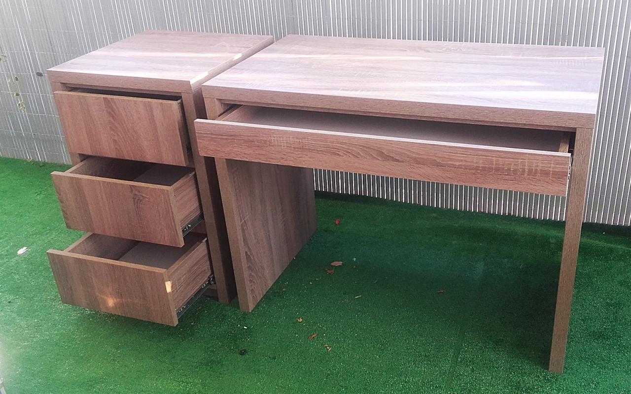 Biurko z szufladami z płyty drewnopodobnej w Lublinie, z wysuniętymi szufladami, na tle zielonej sztucznej trawy i szarego płotu.