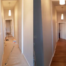 Korytarz w trakcie remontu: część ściany pomalowana na szaro, podłoga zabezpieczona folią malarską, widoczne wiadro z farbą i narzędzia malarskie, druga część korytarza po remoncie z pomalowanymi...