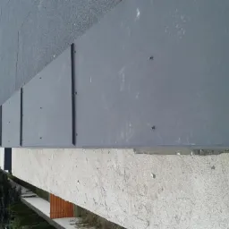 Szary panel obróbki blacharskiej na dachu domu w Płońsku, widoczne łączenia i mocowania.