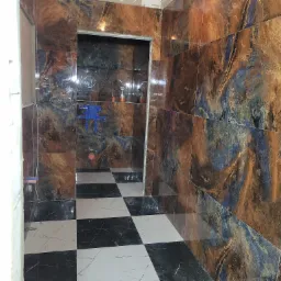 Wykończona łazienka z błyszczącymi, wzorzystymi brązowo-niebieskimi płytkami na ścianach i podłodze w szachownicę. Widok na kabinę prysznicową.