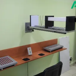 Aparat do badania widzenia stereoskopowego i koordynacji wzrokowo-ruchowej, z panelami kontrolnymi na drewnianym blacie i logo w rogu.