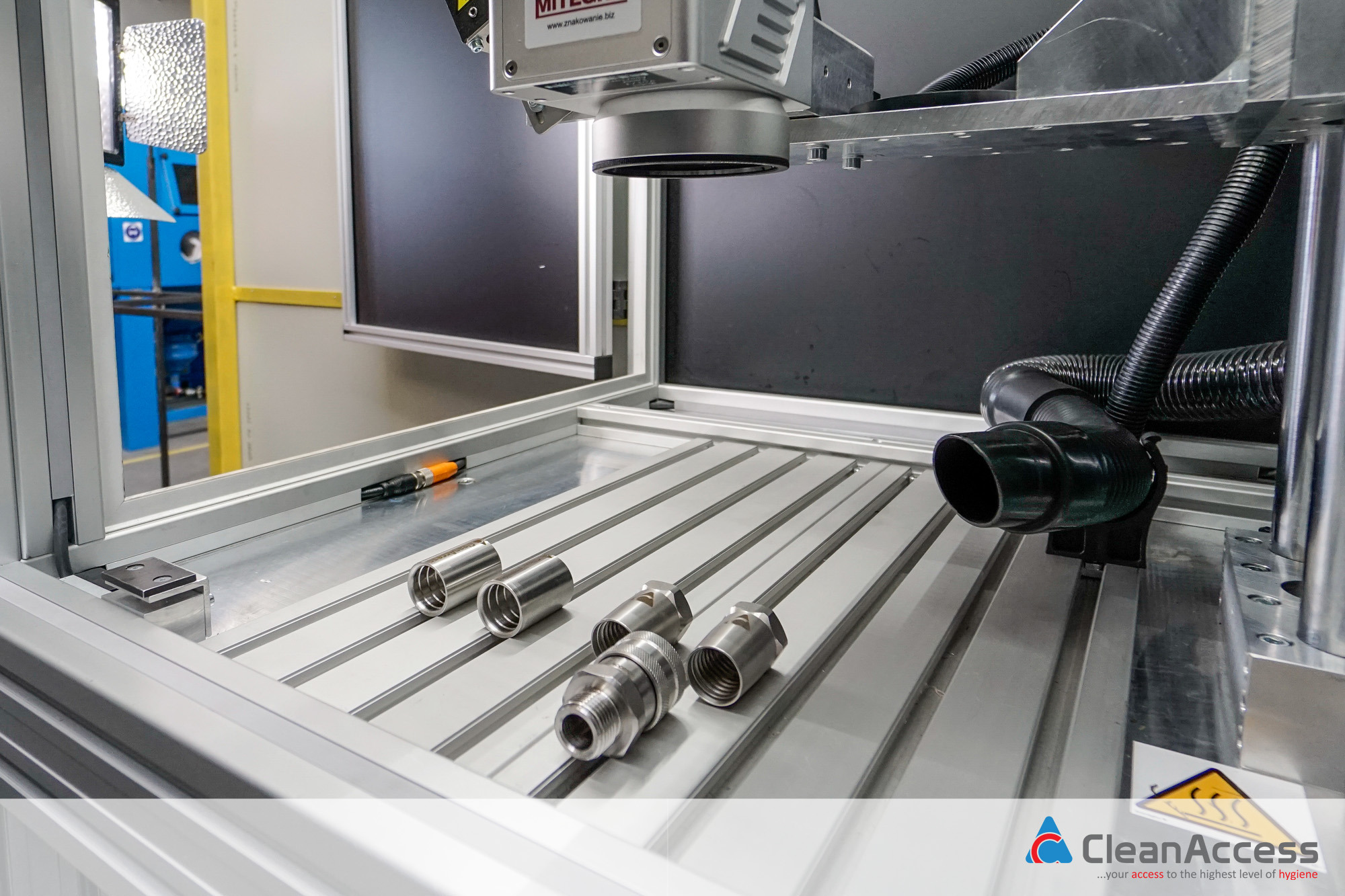 Precyzyjna obróbka CNC: Metalowe tuleje i złączki na aluminiowym stole frezarki CNC, widoczny czujnik pomiarowy i system odciągu wiórów.