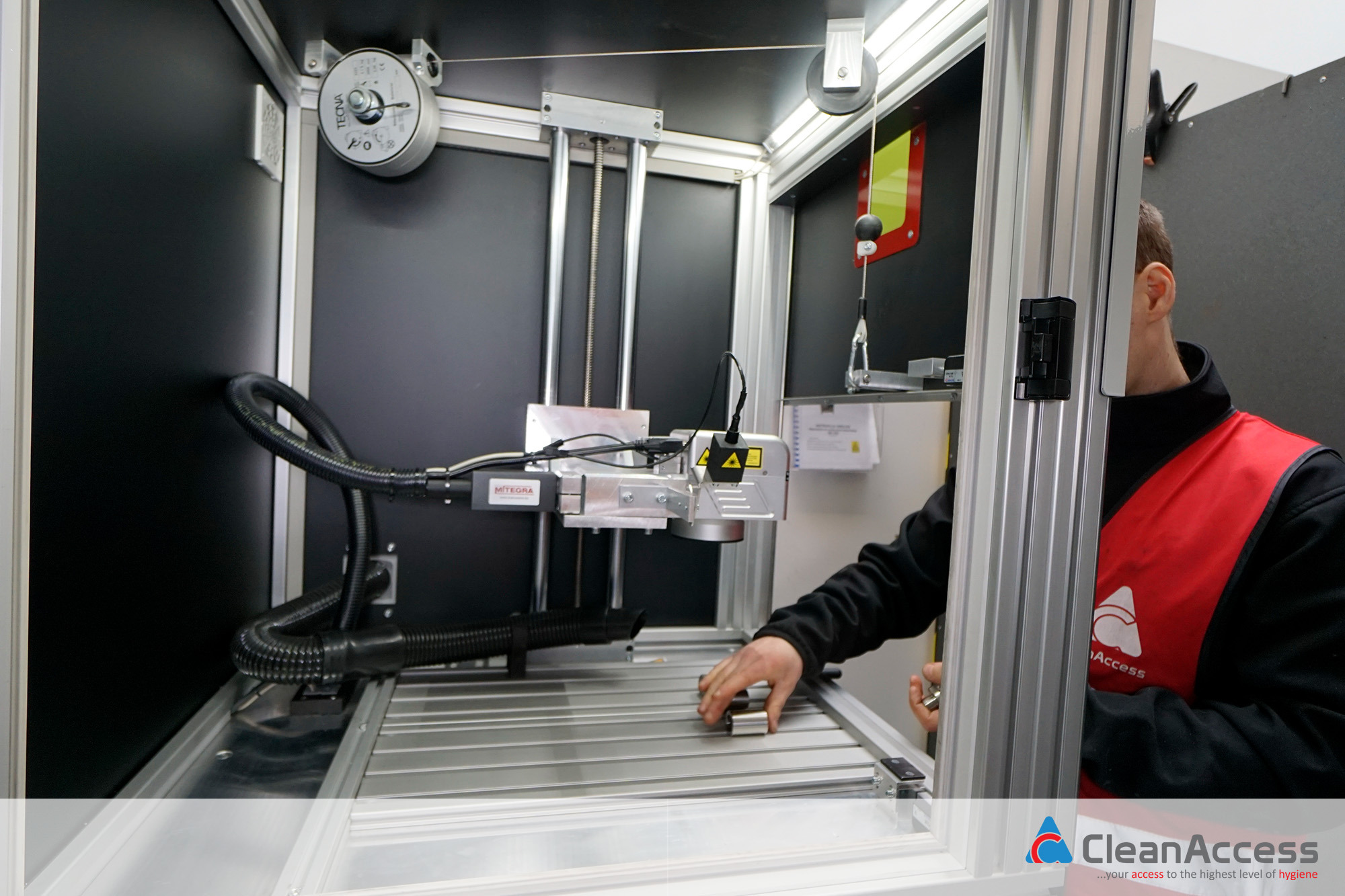 Pracownik umieszcza metalowe elementy na stole roboczym pod laserową głowicą wewnątrz precyzyjnej maszyny do obróbki metali.