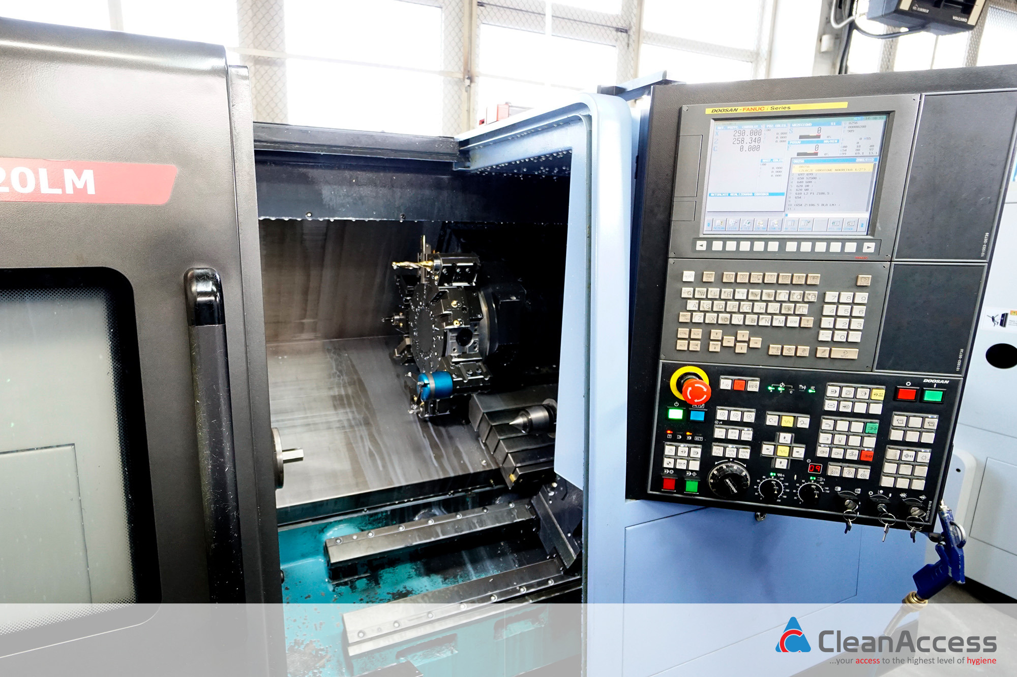 Wnętrze tokarki CNC Doosan Fanuc Series z widocznym uchwytem narzędziowym i panelem sterowania z wyświetlaczem oraz klawiaturą, oświetlone światłem dziennym.