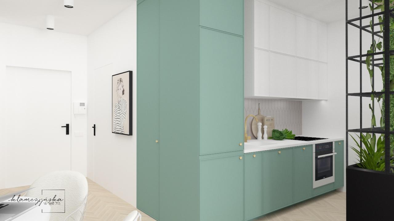 Wizualizacja kuchni w odcieniach bieli i pastelowej zieleni z elementami dekoracyjnymi, takimi jak złota bateria, minimalistyczna grafika na ścianie i roślinność w czarnej, metalowej konstrukcji.