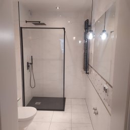 LUX GROUP SPÓŁKA Z O.O. - Nowoczesna łazienka z kabiną prysznicową typu walk-in z czarną ramą, grzejnikiem drabinkowym i wiszącymi lampami kulami.