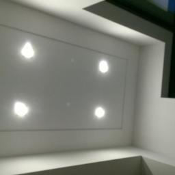 Cis-Bud - Biały sufit podwieszany z wbudowanymi czterema punktowymi lampami LED, widok z dołu, fragment okna z ciemną ramą