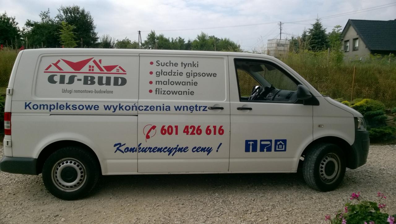 Biały samochód dostawczy firmy CIS-BUD z reklamą usług remontowo-budowlanych, w tym suche tynki i kompleksowe wykończenia wnętrz, zaparkowany na żwirowym podjeździe przed domem.