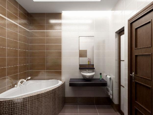 Nowoczesna łazienka z brązowo-białymi płytkami, owalną wanną obudowaną mozaiką, wiszącą umywalką na czarnym blacie i dużym lustrem bez ramy.
