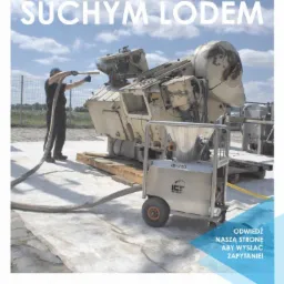 Pracownik w kombinezonie czyszczący dużą maszynę przemysłową metodą strumieniowania suchym lodem, przy użyciu specjalistycznego urządzenia mobilnego.