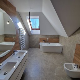 Tom-Fliz - Nowoczesna łazienka na poddaszu z wanną wolnostojącą, umywalką nablatową i bidetem. Uwagę zwraca duże lustro o zaokrąglonym kształcie i okno dachowe.