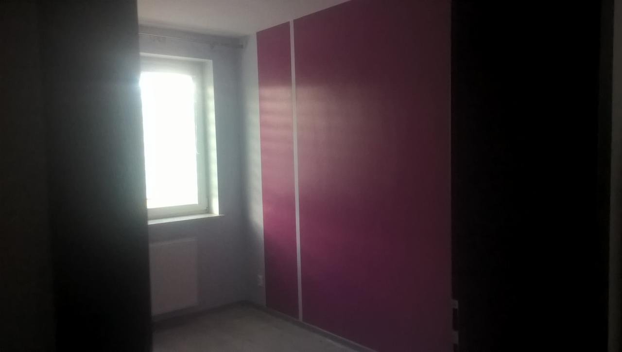 Pomieszczenie w Karolówce po malowaniu ścian na fioletowo z białymi pasami pionowymi, widok na okno z grzejnikiem. Świeżo pomalowane ściany.