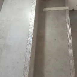 Montaż płyt gipsowo-kartonowych na schodach, widoczne profile i taśma malarska zabezpieczająca powierzchnię.