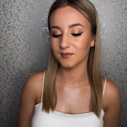 MakeupArtist Ewelina Sojka - Portret kobiety z delikatnym, złotym makijażem oczu, czarną kreską i błyszczącymi ustami. Uwagę zwraca precyzyjny kontur i stonowana kolorystyka.