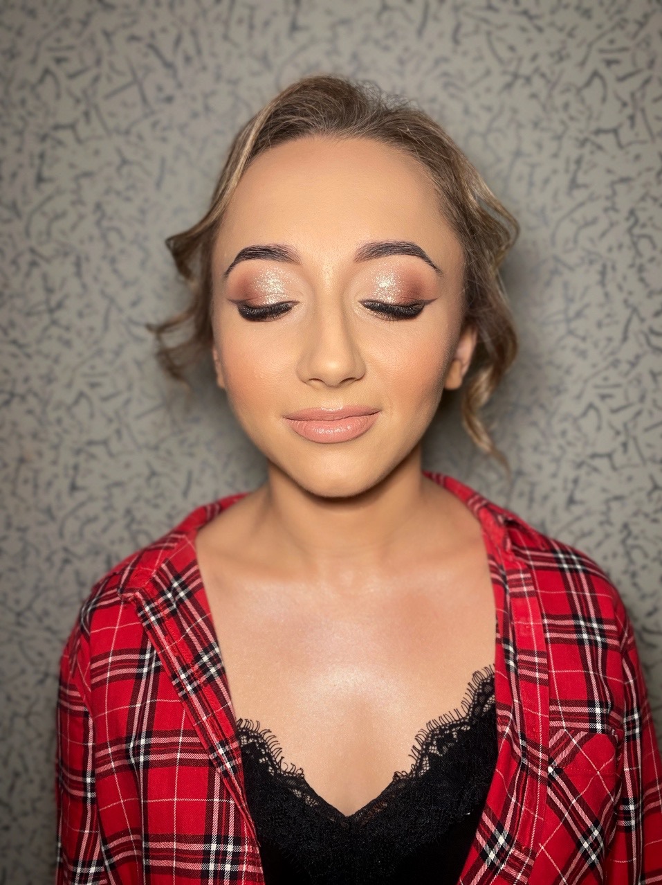 Portret kobiety z zamkniętymi oczami prezentującej delikatny, błyszczący makijaż oczu z wyraźną kreską i subtelnie podkreślonymi ustami w naturalnym odcieniu.