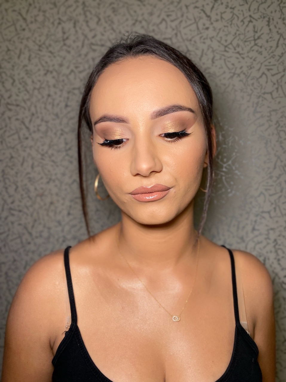 Portret kobiety z profesjonalnym, wieczorowym wizażem: złote cienie, wydłużone rzęsy i błyszczące usta. Delikatna biżuteria podkreśla stylizację.