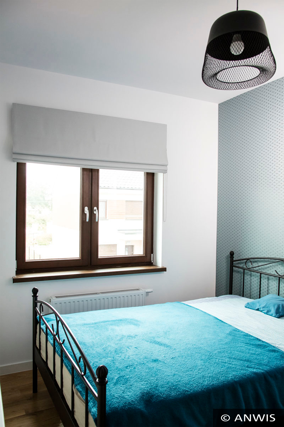 Jasnoszara, płaska osłona okienna w pokoju z niebieskim akcentem kolorystycznym, widok na budynek z zewnątrz.