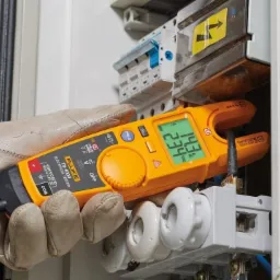 Pomiar napięcia w instalacji elektrycznej w Bielsko-Białej za pomocą cęgowego multimetru Fluke T6-1000 przez osobę w rękawicach ochronnych.