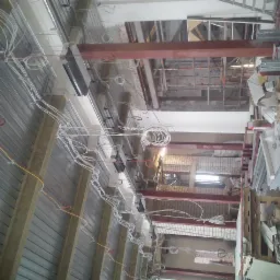 Montaż instalacji elektrycznej w budynku w trakcie prac wykończeniowych, widoczne kable, profile metalowe i materiały izolacyjne.