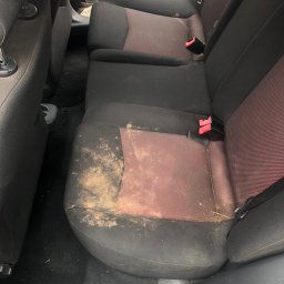 pranietapicerki-bydgoszcz - Silnie zabrudzona, tylna kanapa samochodowa z plamami i resztkami. Widoczne pasy bezpieczeństwa. Tapicerka wymaga czyszczenia.