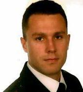 Portret mężczyzny w koszuli, z krótkimi włosami, na jasnym tle. Zdjęcie o obniżonej jakości.