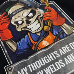 Czarny T-shirt z nadrukiem przedstawiającym szkielet spawacza w hełmie i rękawicach, trzymającego palnik spawalniczy, z napisem 'MY THOUGHTS ARE DIRTY MY WELDS ARE'
