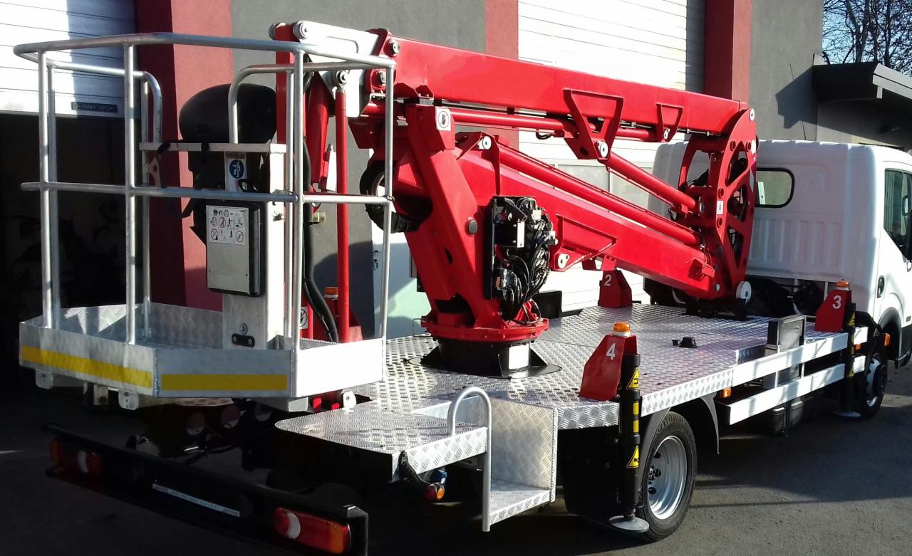 Czerwony podnośnik na samochodzie z aluminiową platformą, widoczne elementy hydrauliczne i sterujące, srebrna klatka platformy roboczej z żółtymi pasami ostrzegawczymi.