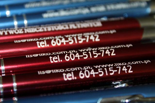 Bliski plan czerwonych i niebieskich długopisów z nadrukowanym adresem e-mail i numerem telefonu firmy.