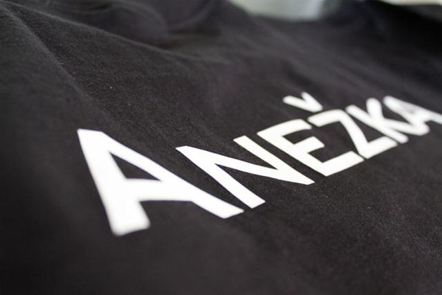 Czarna koszulka z białym nadrukiem imienia 'Anežka' pod kątem, widoczna faktura materiału.