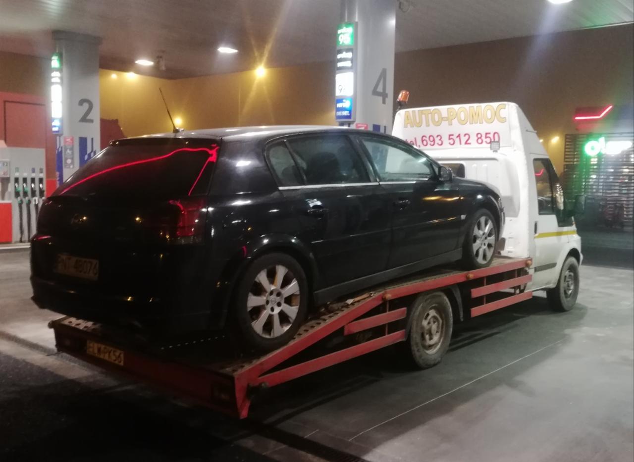 Czarny samochód osobowy Opel Vectra C na czerwonej lawecie Auto-Pomoc z numerem telefonu, na stacji benzynowej w nocy.