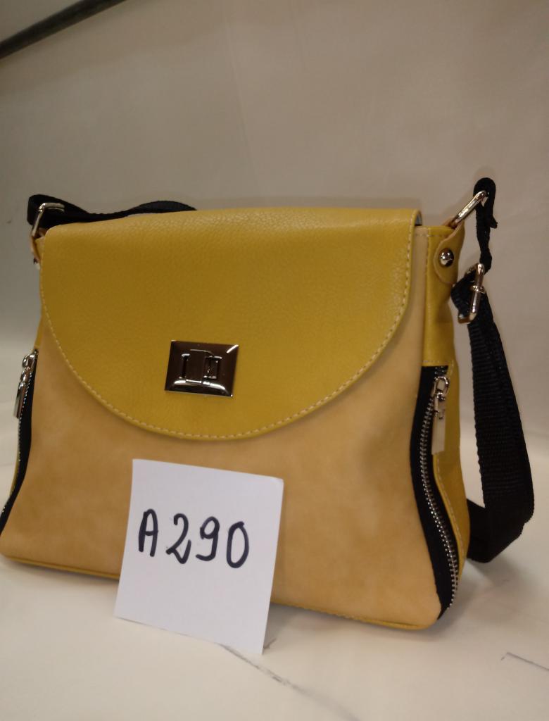 Żółto-beżowa torebka damska z klapką, srebrnym zapięciem i czarnymi zamkami po bokach, na białym tle, z kartką z napisem 'A290'.