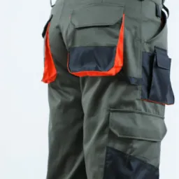 Zielone spodnie robocze z wieloma kieszeniami, czarnymi wzmocnieniami i pomarańczowymi detalami, widok z tyłu na białym tle.