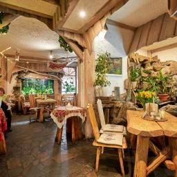 Restauracja Karpielówka - Wnętrze restauracji z wystrojem w stylu rustykalnym: drewniane meble, kamienne elementy dekoracyjne, akwarium i rośliny doniczkowe.