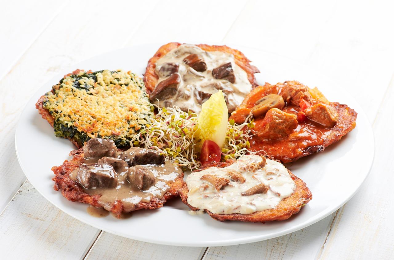 Kompozycja pięciu placków ziemniaczanych z różnymi dodatkami i sosami na białym talerzu, udekorowana kiełkami i sałatą, na tle białych desek.