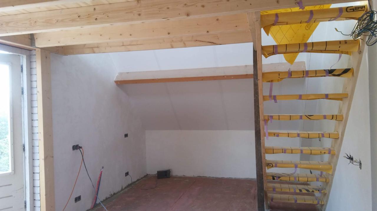 Poddasze w trakcie wykończenia: drewniana konstrukcja stropu, surowe ściany przygotowane do malowania, prowizoryczne schody zabezpieczone folią malarską.