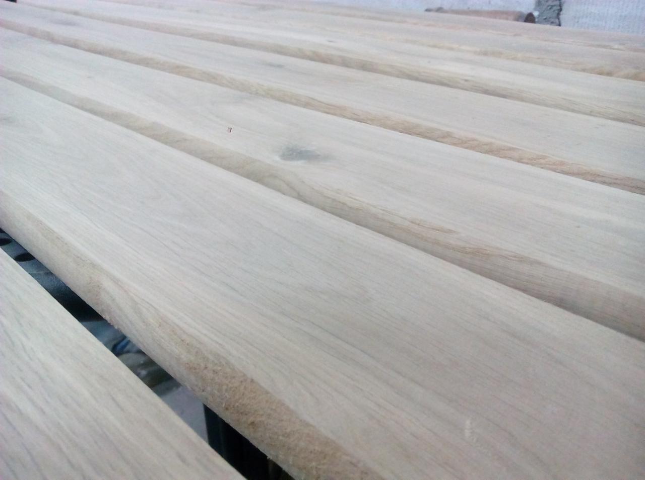 Przygotowane deski z widocznym usłojeniem, prawdopodobnie do budowy ogrodzenia, leżące równolegle obok siebie.