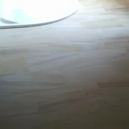 Wykończona łazienka z drewnopodobnymi płytkami, owalną umywalką i dekoracyjną płaskorzeźbą lwa nad nią.